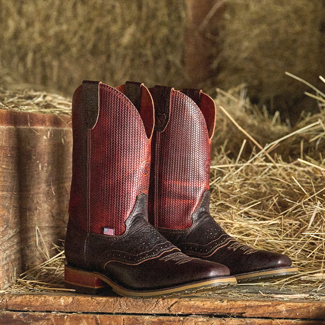 The Baler western boot in brown next to hay.